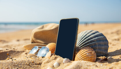 summer holiday concept with smartphone, sunglasses and hat on the beach