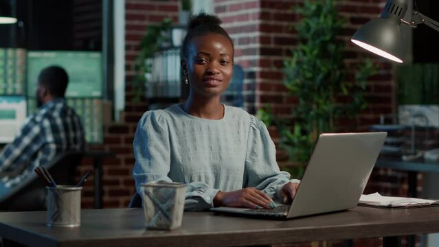 Portrait of african american woman working with stock exchange statistics on laptop, using forex market trading numbers to analyze financial profit. Hedge fund investment price.