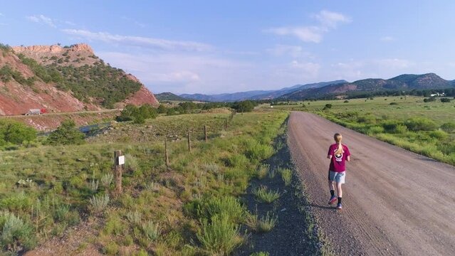 Aerial of woman running on a dirt road in USA