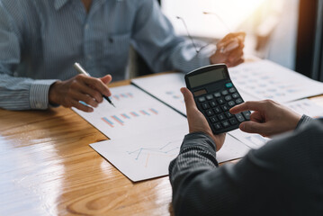 Businessman pointing graph and using calculator during a business meeting.