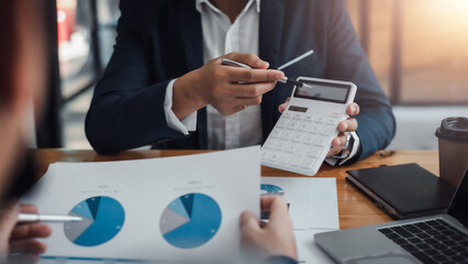 Businessman pointing graph and using calculator during a business meeting.