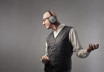 bald man listens to music and pretends to play the guitar