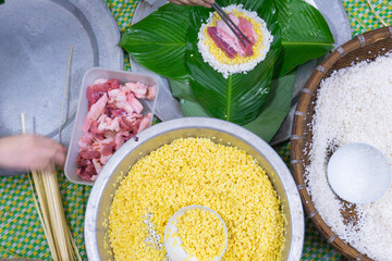 Making chung cake - A traditional food in Tet holiday- Vietnam including green beans, glutinous rice, pork, and pepper wrapped in dong leaves, passed down through generations.
