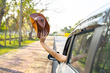 Happy enjoy and freedom in traveling trip with raised hand and holding cowboy hat outside of window...