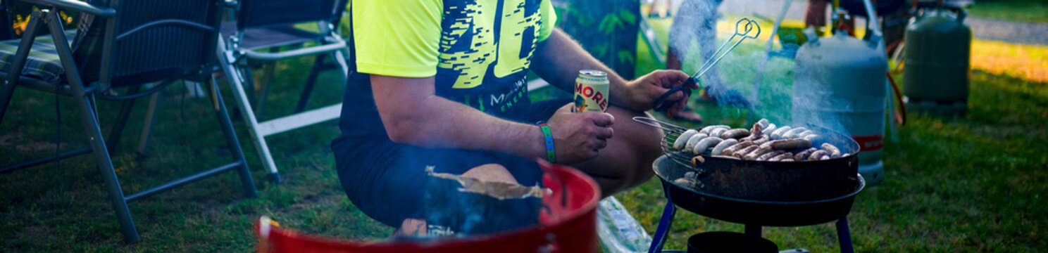 Mann mit Bierdose in der hand und beim Grillen von Fleisch