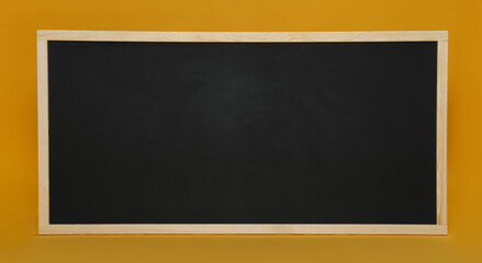 Clean black chalkboard on orange background. School equipment