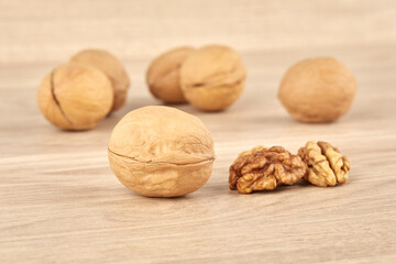 Walnuts on a wooden background, whole and peeled walnut in the foreground
