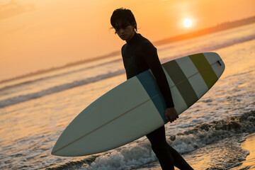 朝の海でサーフィンをする男性