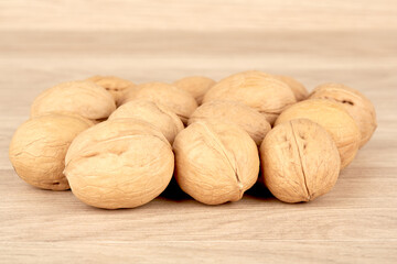 Many walnuts lie in a heap on a wooden background