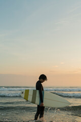 Fototapeta na wymiar 朝の海でサーフィンをする男性