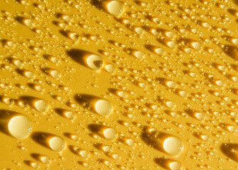 yellow surface covered with water drops with long shadows. Abstract background with raindrops.