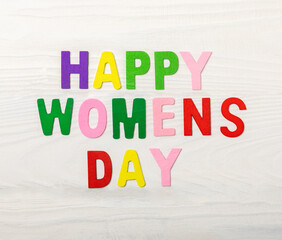 International Women's Day. Beautiful postcard for March 8. Happy women's day text on white texture wood. Holiday concept. Copy space. View from above.