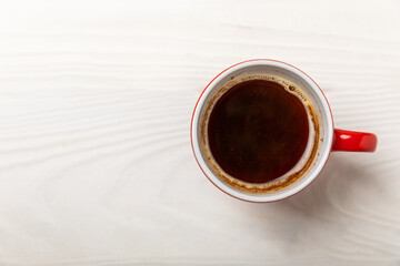 A cup of fragrant hot coffee on a white textured wood.Hot warming drink. Good morning. Morning concept. View from above. Place to copy.