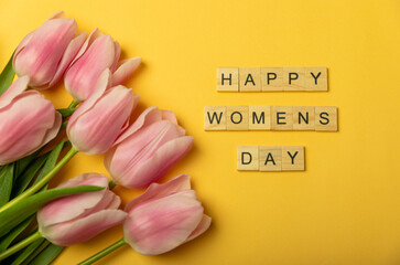 International Women's Day. Beautiful postcard for March 8. Spring bouquet of pink tulips with the inscription Happy Women's Day on a yellow background. Holiday concept. Copy space. Flatley