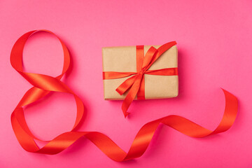 March 8, International Women's Day. Number eight from a red ribbon and a gift box with a satin ribbon on a pink paper background. Place for text