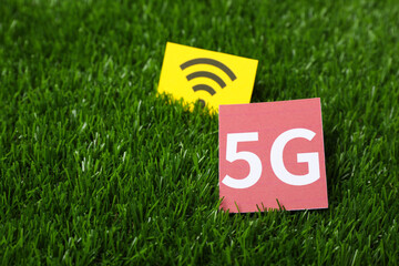 5G technology, Internet concept. Cards with WiFi symbol on green grass, closeup. Space for text