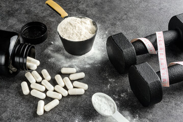 protein scoop, creatine capsules and dumbbells with measuring tape. The concept of the usefulness...