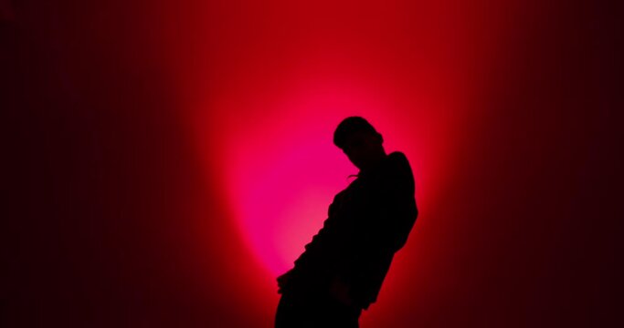 Silhouette of young man dancing in red light background