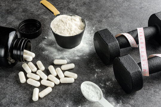 protein scoop, creatine capsules and dumbbells with measuring tape. The concept of the usefulness of sports nutrition.