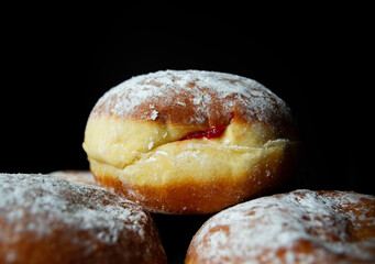 Polish pączki (deep-fried doughnuts). Celebrating Fat Thursday (Tłusty czwartek) feast, traditional day in Poland. Pączek food, powdered sugar topped and filled with rose hip jam.