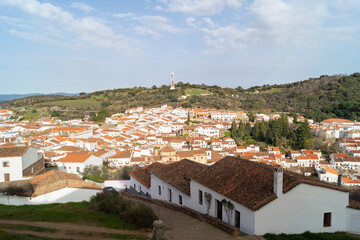 Fototapeta na wymiar View of the beautiful village of Aracena (Andalusia, Spain). Village with white-walled houses and tiled roofs surrounded by nature. Village on a hill illuminated on a sunny day.