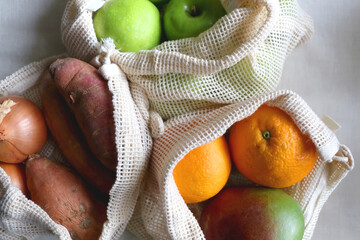 Reusable mesh bags filled with various healthy fruit and vegetable. Top view. 
