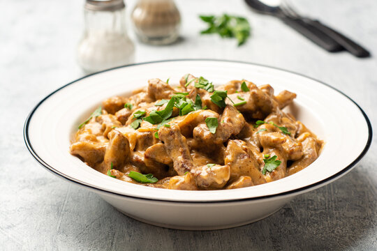 Traditional Russian dish Beef stroganoff in plate on concrete background