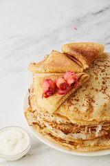 Crepes with smoked salmon on a white plate. pancakes with salmon and sour cream on a gray background. Pancakes with red fish for carnival.