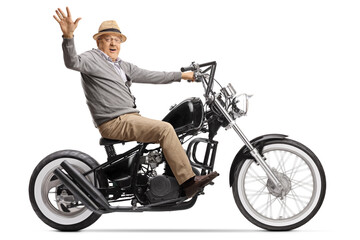 Fototapeta na wymiar Senior man riding a custom chopper motorbike and waving at the camera