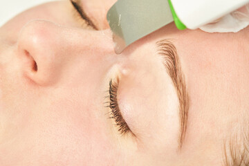 Ultrasound cosmetology scrubber. Face cavitation procedure. Salon skincare treatment. Professional...