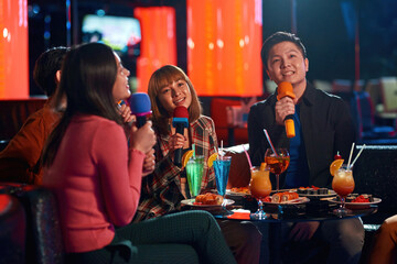 Asian friends enjoying friendship together in karaoke bar