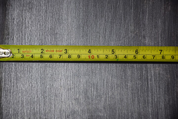 The yellow tape measure is measured in centimeters, measuring the size of a gray-black steel plate
