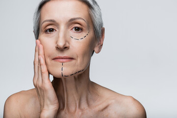 mature woman with wrinkles and marked lines touching face isolated on grey
