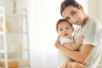 White text copyspace background with a tender portrait of a happy beautiful young mom holding her cute baby in her arms. Family, children, Mother's day, love, and care concepts