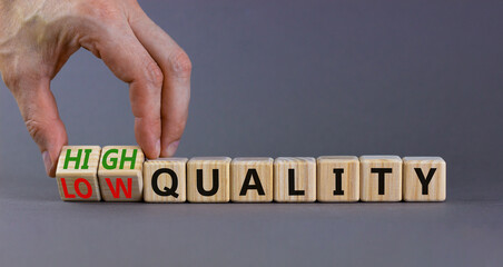 Low or high quality symbol. Businessman turns cubes and changes words low quality to high quality. Beautiful grey table grey background. Business low or high quality concept, copy space.