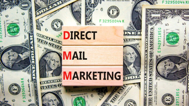 DMM direct mail marketing symbol. Concept words DMM direct mail marketing on wooden blocks on a beautiful background from dollar bills. Business and DMM direct mail marketing concept. Copy space.