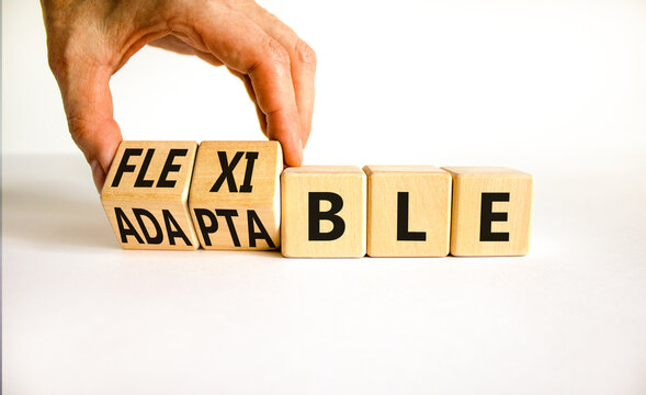 Adaptable Or Flexible Symbol. Businessman Turns Wooden Cubes And Changes The Word Adaptable To Flexible. Beautiful White Table White Background, Copy Space. Business, Adaptable Or Flexible Concept.