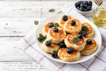 Cottage cheese fritters with blueberries on wooden background with copy space