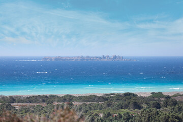 Obraz premium Empty wild beach on the Aegean coast with colorful bushes in the foreground. Unusual space seascape
