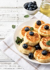 Cottage cheese fritters with blueberries on wooden background with copy space