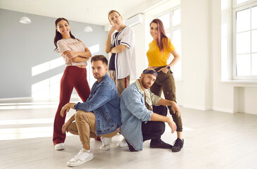 Team of young people posing in dancing studio. Modern dance crew members in informal outfits. Indoor group portrait of talented contemporary, hip hop and break dance instructors, coaches and experts