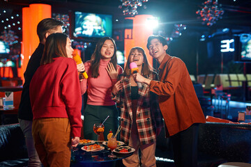 Group of young asian people enjoying at karaoke nightclub