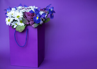 White and blue flowers in a purple bag on a purple paper background. Place for text