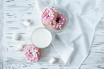 a glass of milk and marshmallow donuts lie on a white napkin on a wooden background. Sweets, delicious
