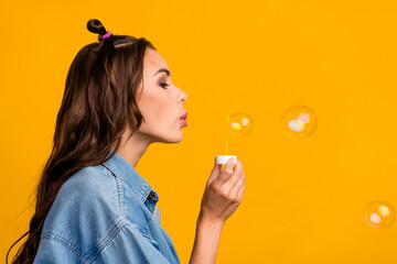 Profile side photo of young pretty woman blow bubbles free-time isolated over yellow color...