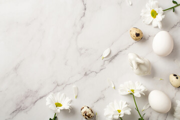 Top view photo of easter decorations chrysanthemum flowers petals ceramic easter bunny statuette white and quail eggs on isolated white marble texture background with copyspace