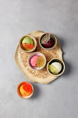 Assorted ice cream balls in ceramic dishes. Frozen dessert - ice cream with vanilla, pistachio, mango, blueberry and strawberry flavours on gray stone background