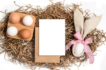 Easter mockup greeting card with bunny ears and easter eggs on white background. Flat lay, top view, copyspace.