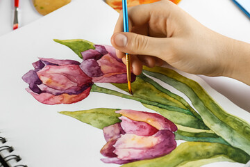 Woman painting tulips in sketchbook, closeup view