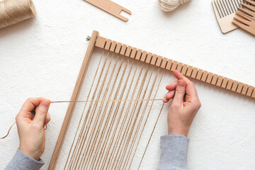 Female hands tucking a frame for weaving